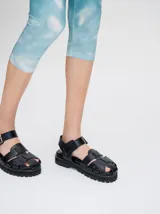 Sandalias romanas de cuero tostado, estilo chunky con plataforma y suela tractora de goma negra. Cuentan con tiras cruzadas en el empeine y tira ajustable con hebilla metálica en el tobillo.