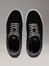 Zapatillas urbanas Calvin Klein Jeans de ante negro con logo CK grabado en el lateral, detalle de talón en gris, cordones grises y suela cupsole blanca.