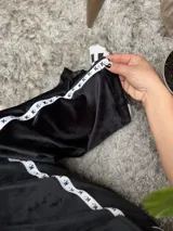 Pantalón de jogging negro de plush, con elástico en la cintura, bolsillos laterales y cinta con logo a lo largo de la pierna.