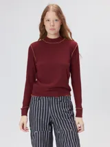 Remera de cuello alto tipo polera, confeccionada en tela rib con textura acanalada y ajuste al cuerpo. Presenta mangas largas y un pequeño bordado distintivo en la parte inferior.