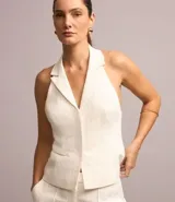 Chaleco blanco de tweed texturizado con espalda abierta, botones delanteros y solapas.