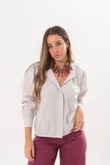 Camisa beige a rayas finas de manga larga, con cuello camisero y cierre frontal oculto.