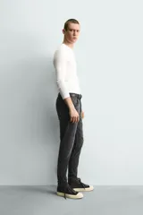 Jeans skinny fit de corte ajustado y tiro medio en color negro con efecto lavado y detalles desgastados. Confeccionados en tejido elástico con mezcla de algodón, presentan diseño clásico de cinco bolsillos y cierre frontal con cremallera y botón.