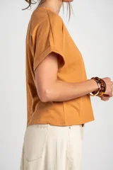 Remera color camel, de corte al cuerpo, manga corta con vuelta y cuello redondo.