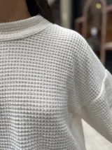 Polera de tejido de punto con textura tipo waffle, color crudo, de corte holgado y mangas anchas con puños acampanados.