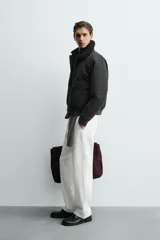 Cazadora bomber de corte cropped confeccionada en algodón, color negro. Presenta cuello de solapa con efecto borreguillo a contraste, cierre frontal con cremallera metálica, bolsillos delanteros tipo plastrón con solapa y acabados en rib en puños y bajo.