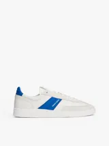 Zapatillas deportivas de estilo vintage Tommy Jeans modelo The Greenwich, confeccionadas en ante color blanco con paneles laterales en azul vibrante y detalles en gamuza gris claro. Presentan cierre con cordones, suela cupsole de goma y logo de la marca en el lateral.