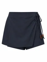 Short pollera de tiro alto, simil lino, con diseño cruzado tipo falda envolvente y lazos laterales decorados con cuentas de madera.