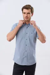 Camisa de manga corta de algodón en color celeste con microdiseño geométrico a cuadros, cuello camisero y bolsillo frontal con logo bordado.