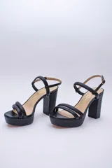 Sandalia de cuero con plataforma y taco cuadrado alto. Presenta una tira delgada en el tobillo con cierre de hebilla metálica y dos tiras acolchadas en la parte frontal.