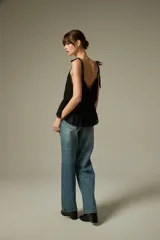 Musculosa negra de breteles finos, confeccionada en algodón con diseño plisado y detalles de encaje. Presenta un corte holgado con volados en el ruedo y escote profundo.