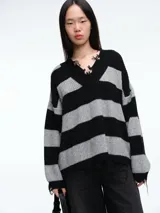 Sweater de tejido de punto con diseño a rayas horizontales en negro y gris. Presenta cuello en V con terminaciones desflecadas, corte holgado y mangas largas con puños desflecados.