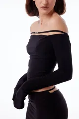 Top negro con cuello bote, hombros descubiertos y mangas largas.