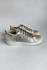 Championes de cuero de diseño artesanal, combinados en tonos plateado, dorado y natural. Presentan detalles pintados a mano por Carolina De Cunto, cordones al tono, suela de goma blanca y aplique metálico con logo en el lateral.