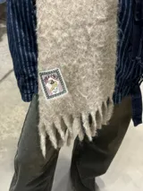 Bufanda beige de tejido esponjoso con flecos en los extremos.