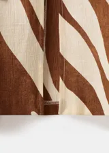 Vestido midi con estampado animal print tipo cebra en tonos marrón y blanco, de corte recto, con escote en V, mangas tres cuartos y tajo delantero en la falda. Incluye un cinturón fino ajustable.
