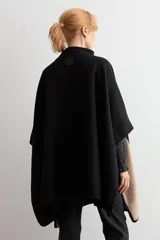 Capa de corte amplio y diseño bicolor, combinando negro en la parte frontal y trasera con paneles laterales en color beige. Presenta cuello alto y cierre frontal con hebilla metálica.