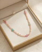 Collar de acero con baño de oro, compuesto por pequeñas cuentas de piedras naturales en tonos pastel y detalles metálicos dorados.