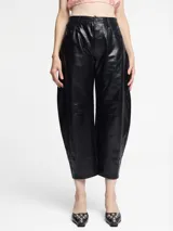 Pantalón de silueta globo confeccionado en cuero sintético con acabado efecto vintage. Presenta un corte de pierna ancha, tiro medio y cierre frontal con botón y cremallera.