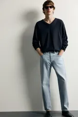 Jeans regular fit confeccionados en denim de algodón celeste con efecto lavado, de cinco bolsillos y cierre frontal con cremallera y botón.