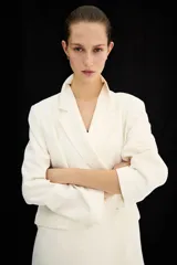 Blazer levemente largo color blanco con solapas de muesca, botones delanteros, hombreras y bolsillos delanteros ribeteados con solapa. Diseño cruzado y forrado.