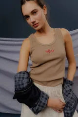 Musculosa básica de tejido acanalado color blanco, con escote redondo, calce al cuerpo y el logo NSLD bordado en el centro del frente.