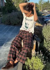 Pantalón de viyela a cuadros en tonos marrón y negro, de corte ancho y recto. Tiene botón en la pretina delantera y elástico en la parte trasera de la cintura.