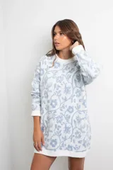 Vestido tejido de punto con diseño oversize, estampado floral en tonos celeste y blanco, cuello redondo y mangas largas con puños acanalados.