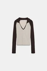 Camiseta de manga larga, corte slim fit, con cuerpo color beige claro y mangas y cuello polo en color marrón oscuro. Presenta un escote en pico bajo el cuello polo.