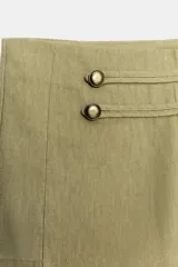 Shorts mini de tiro alto color verde militar, con detalle de botones metálicos y aplicaciones en la parte delantera.