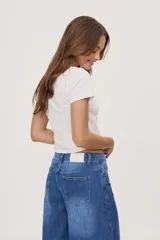 Jean de tiro medio y corte barrel con pierna amplia y ligeramente curva, estilo de cinco bolsillos en denim negro lavado.