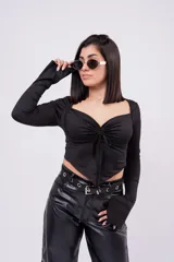 Crop top de manga larga color bordó, confeccionado en tela elastizada. Presenta escote corazón, frunce ajustable con cordón en el centro del pecho y dobladillo inferior en pico. Las mangas largas cuentan con detalle acampanado en los puños.