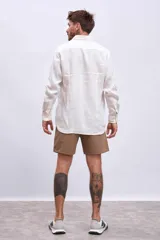 Camisa de lino color crudo, de corte recto, con cuello clásico y mangas largas.