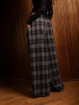 Pantalón tipo palazzo de corte amplio y tiro alto, con diseño de estampado a cuadros tipo tartán en tonos oscuros. Presenta pinzas en la cintura y bolsillos laterales.