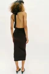 Vestido midi de cuello halter con detalle de drapeado en la cintura y broche metálico dorado en forma de caracola. Presenta cierre ajustable con lazadas en la espalda.