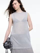 Musculosa de tejido fino y translúcido con sutil brillo metálico, de corte relajado, sin mangas y largo por debajo de la cadera con aberturas laterales.