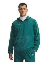 Campera de entrenamiento Under Armour Challenger, color verde esmeralda con detalles en amarillo neón. Presenta media cremallera frontal, capucha, bolsillo frontal con cierre y puños elásticos. Diseño técnico con tecnología repelente al agua y forro de malla.