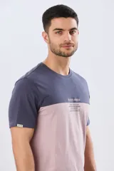 Remera de algodón y poliéster de corte clásico, con diseño en bloques de color negro en la parte superior y gris melange en la inferior. Presenta cuello redondo, mangas cortas y un pequeño estampado tipográfico en el pecho.