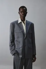 Blazer de corte regular confeccionada en tejido con lana, con cuello de solapas de muesca y manga larga con puños abotonados. Presenta cierre frontal de botonadura y cuatro bolsillos plastrón con solapa en el delantero.