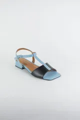 Sandalias de cuero combinadas en negro y marfil, con diseño de tiras en T, taco cuadrado bajo y pulsera con hebilla ajustable al tobillo.
