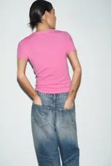 Camiseta rosa de cuello redondo y manga corta con estampado frontal de la frase "I ❤️ BEING DRAMATIC" con strass. Corte slim fit.