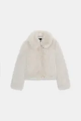 Abrigo corto de piel sintética en color beige, con cuello solapa, manga larga y cierre frontal con cremallera. Incluye bolsillos laterales y forro interior a tono.
