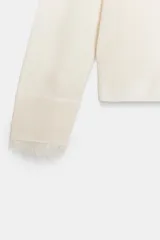 Jersey de punto fino con escote en pico y manga larga. Presenta detalles de encaje a tono en el escote y en los puños.