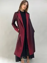 Tapado de paño de lana con diseño de solapas amplias, corte recto y bolsillos laterales ocultos. Presenta un degradado de color que va desde un tono bordó intenso en las solapas y puños hacia un tono más oscuro en el cuerpo.