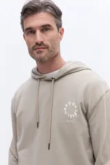 Canguro con capucha de algodón color beige, con cordones de ajuste y estampa circular frontal con el nombre de la marca y el año 1971.