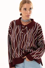 Buzo de punto color vino con diseño de rayas verticales irregulares en tonos claros. Presenta cuello polo con cierre frontal de tres botones, mangas largas con puños acanalados y corte holgado.