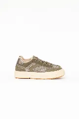 Championes urbanos de cuero legítimo y gamuza color verde oliva, decorados con tachas plateadas en los laterales y la puntera. Poseen suela chunky de goma blanca y cordones al tono.