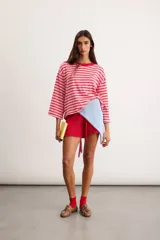 Pañuelo de tejido en hilo de color celeste con bordado artesanal rojo en los bordes, de formato triangular.