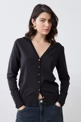 Cardigan de punto negro con escote en V, cierre frontal con botones metálicos dorados y mangas largas con puños ajustados que incluyen detalles de botones decorativos.
