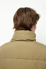 Campera puffer corta color beige de nylon, con cuello alto, cierre frontal y bolsillos laterales con cierre.